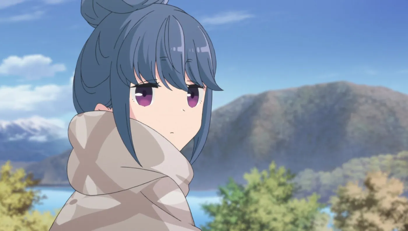 Rin wrapped in a blanket, looking back over a lake and autumn mountains